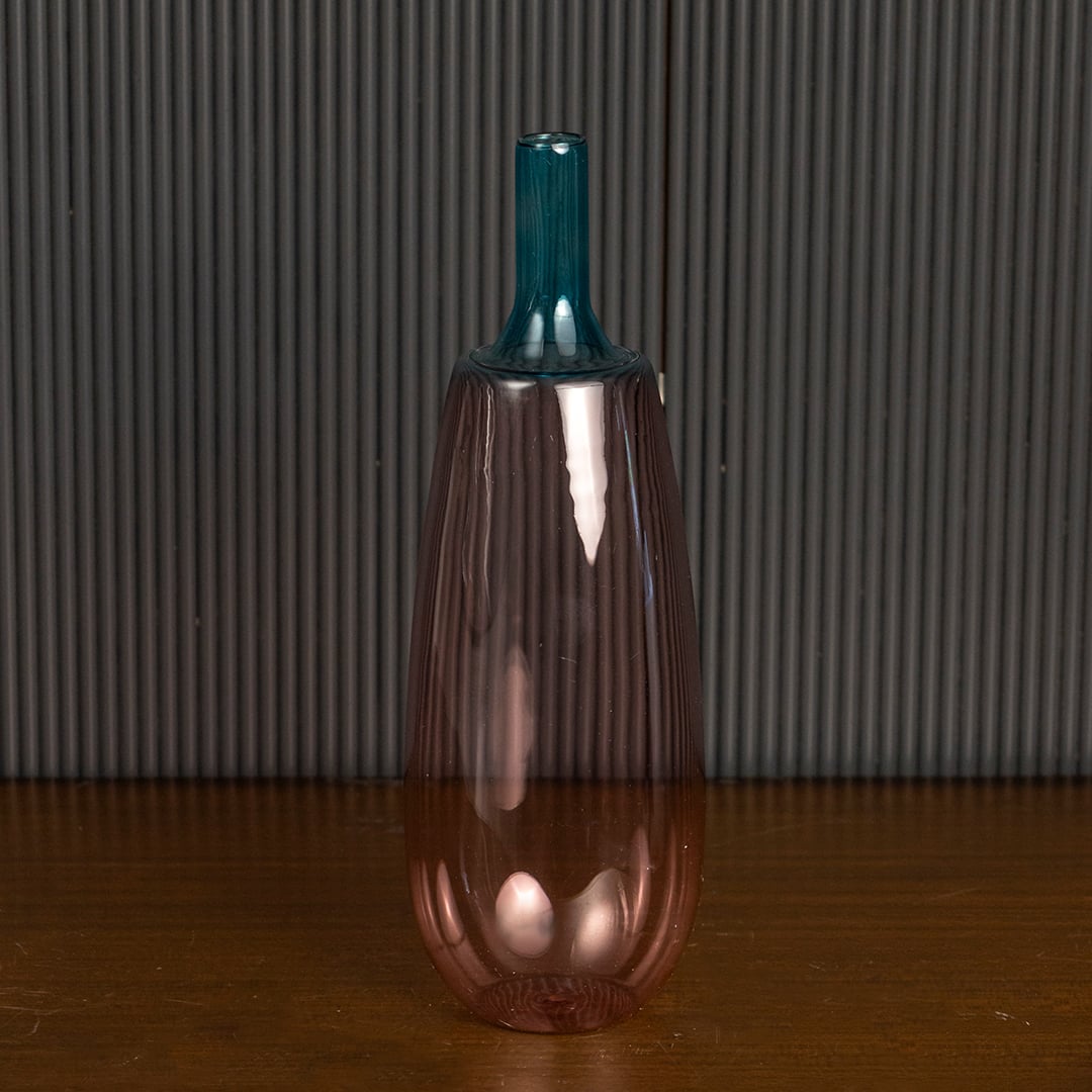 Stylish pink glass vase with blue top highlighted on dark background for luxury home interior styling.