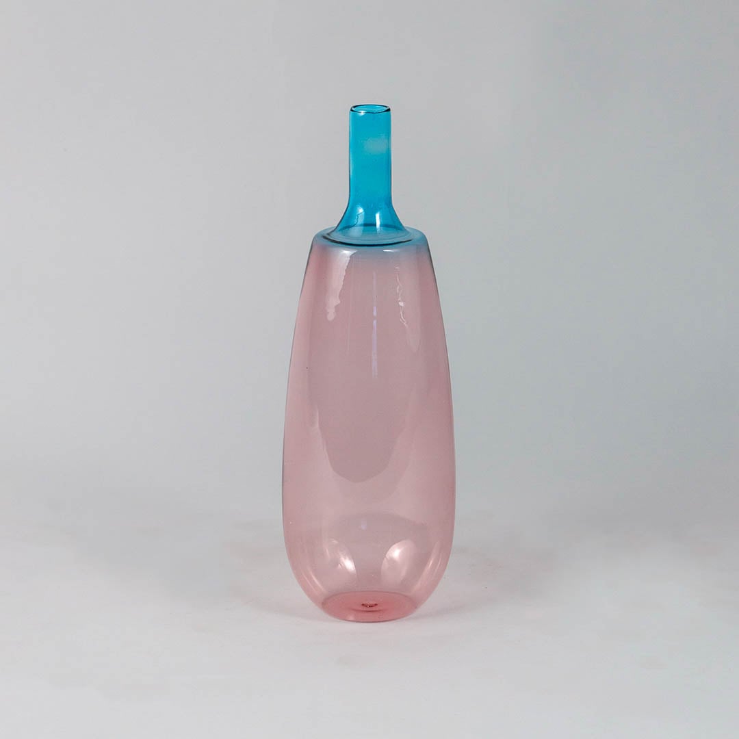 Transparent pink glass vase with blue neck ideal for flower arrangements and modern shelf decoration.