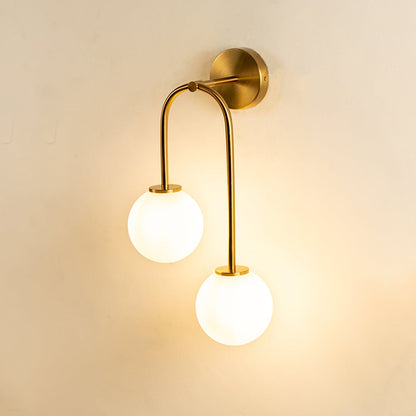 Gold and white glass wall light glowing warmly on white background creating soft ambient lighting.