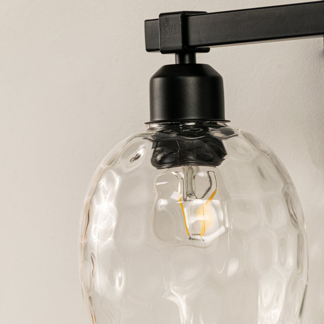Detailed closeup of black double wall light showing textured clear glass shades and sturdy metal frame perfect for stylish modern interior walls.