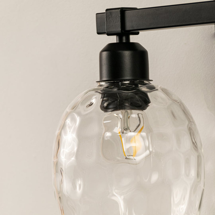 Detailed closeup of black double wall light showing textured clear glass shades and sturdy metal frame perfect for stylish modern interior walls.