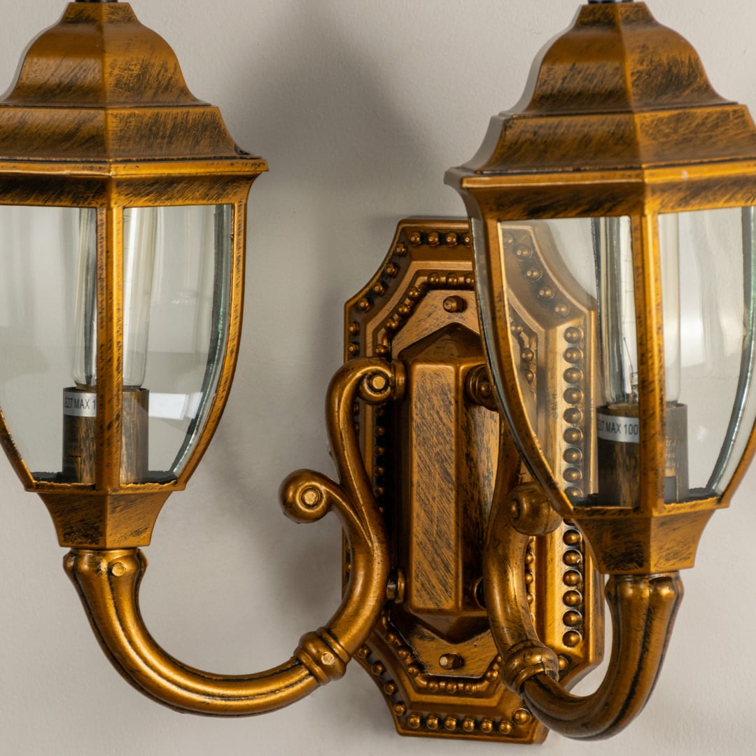 Closeup view of double brass outdoor lantern showing glowing bulbs clear glass panels and antique metal finish for warm elegant entrance lighting.