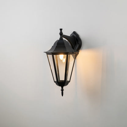 Black metal outdoor wall light on white background with clear glass shade for classic exterior decor.