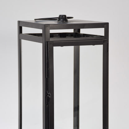 Closeup of black metal lantern with clear glass panels for modern tabletop decor styling use.