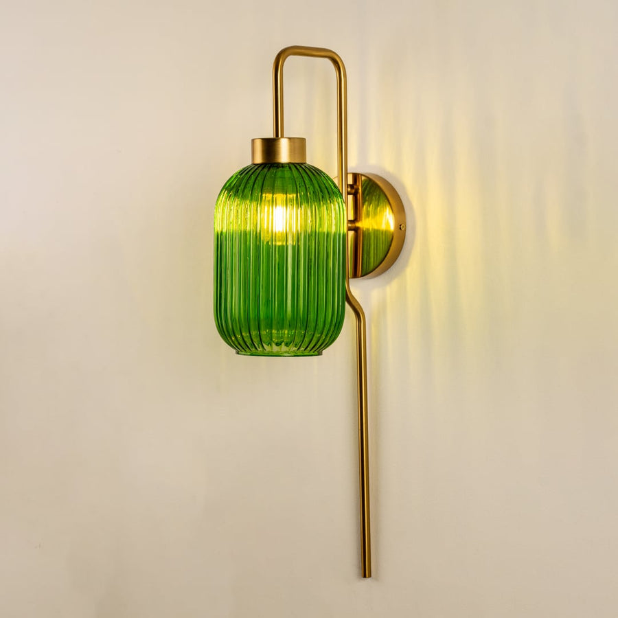 Green ribbed glass wall sconce with extended metal rod glowing softly against a clean white background showcasing modern minimalist interior home decor lighting.