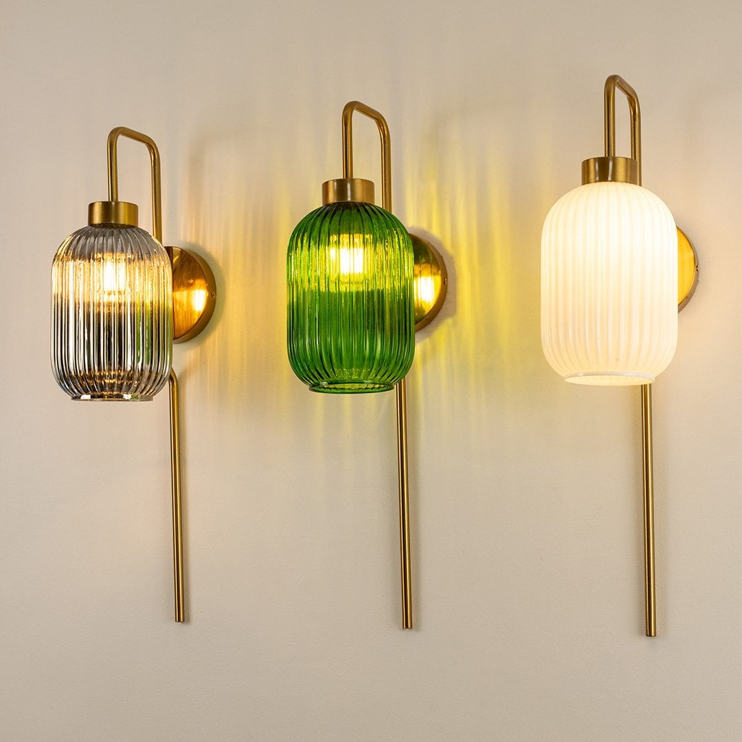Closeup of gold metal wall light illuminated with white ribbed glass shade creating warm glow for luxury interior Decor.