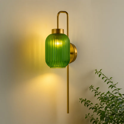 Gold metal wall light with green ribbed glass shade emitting warm glow ideal for bedroom or living room wall decor styling.