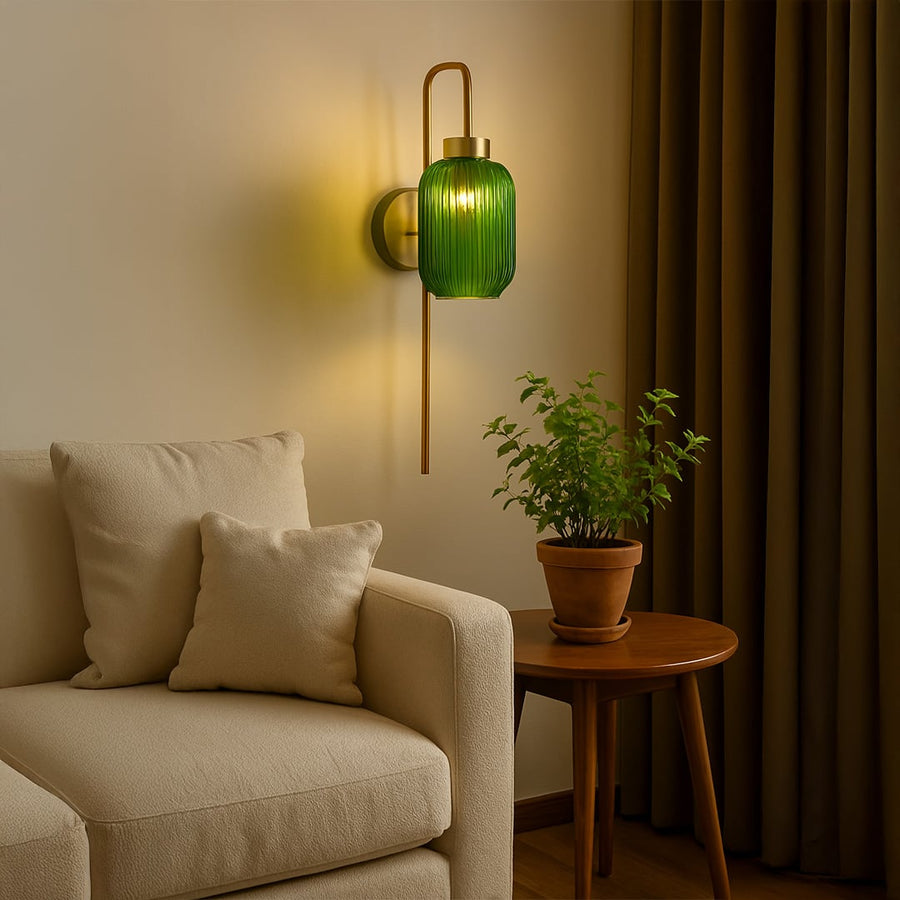Modern green ribbed glass wall sconce with long sleek metal rod creating warm ambient lighting and adding a stylish contemporary touch to elegant interior home decor.