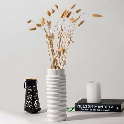 Natural dried bunny tail grass in tall white vase styled with candle and decor accents for boho home decoration.
