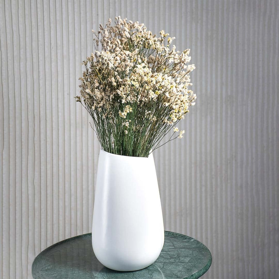 Natural white dried flower bunch held in hand adding soft rustic charm to a bright modern home setting.