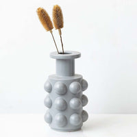 Dried dipsacus thistle stems in a grey bubble vase offering a décor accent perfect for natural boho styling and modern minimalist interior decoration.