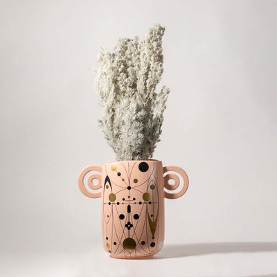 Grey preserved foliage bouquet styled in designer peach ceramic vase lifestyle home decor arrangement background.