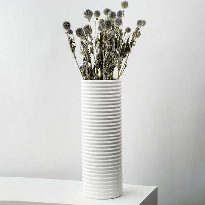 Grey dried globe thistle bouquet preserved flowers styled in tall white ceramic vase lifestyle modern home decor.
