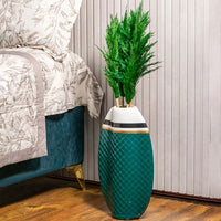 Green pampas grass styled in tall designer vase placed beside bed for luxury home decor and modern styling.