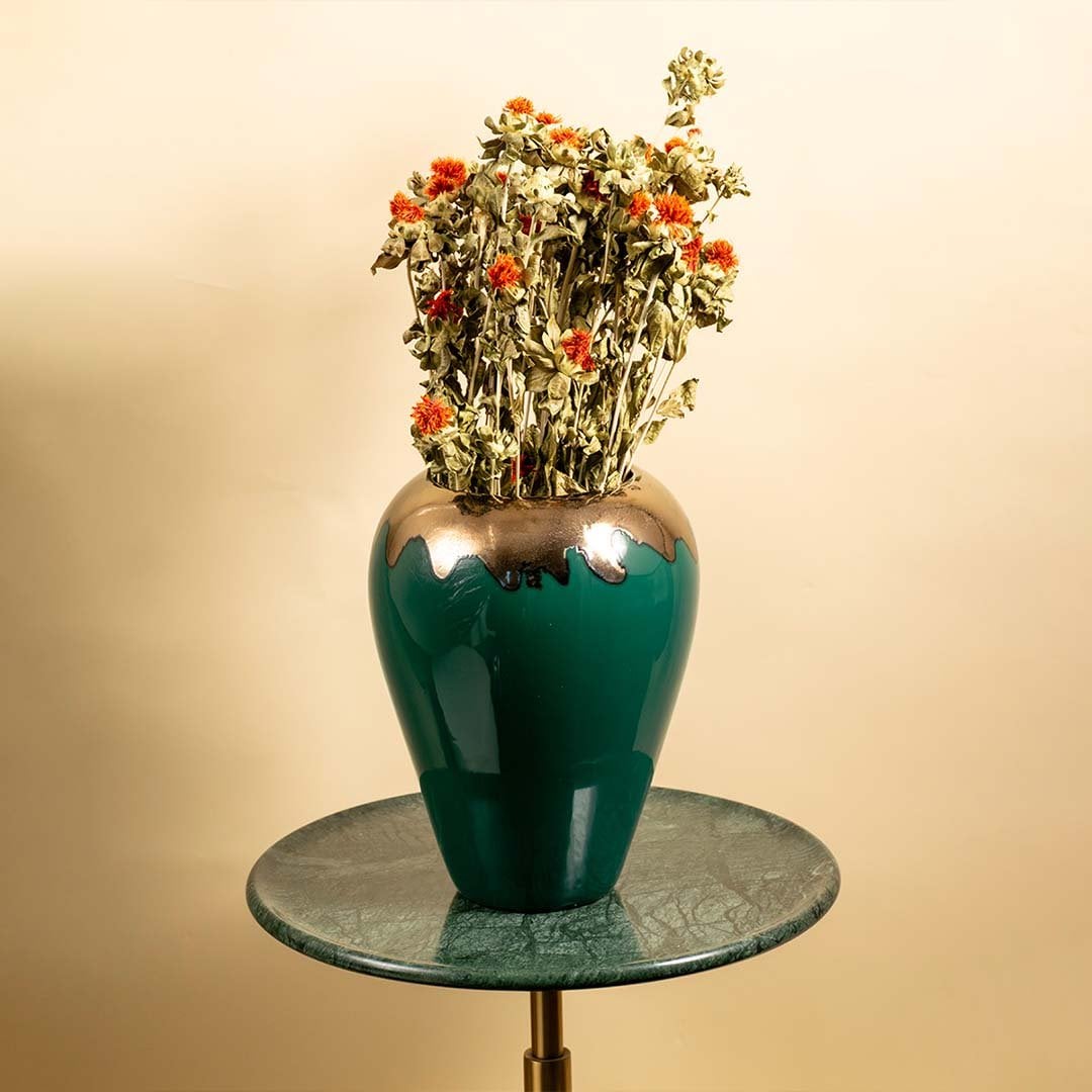 Glossy green ceramic vase with gold detailing and dried orange flowers styled in a cozy living room adding a rich artistic touch to modern interior decor.