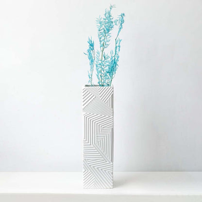 Turquoise preserved foliage stem styled in tall geometric white vase perfect for modern living room floral decor and interiors.
