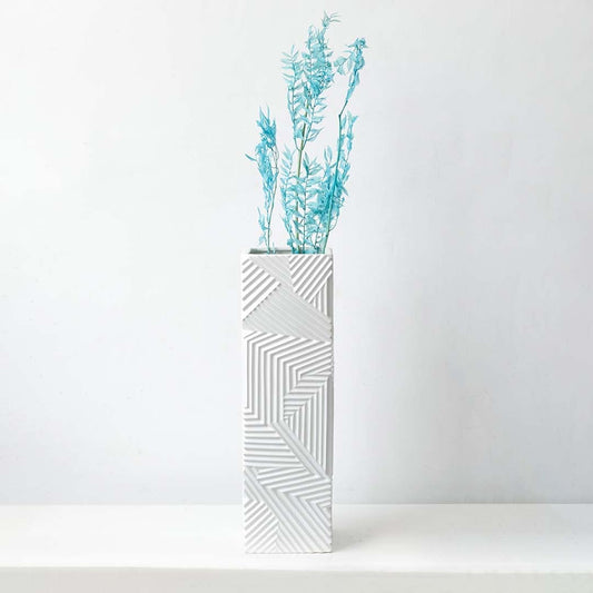 Turquoise preserved foliage stem styled in tall geometric white vase perfect for modern living room floral decor and interiors.