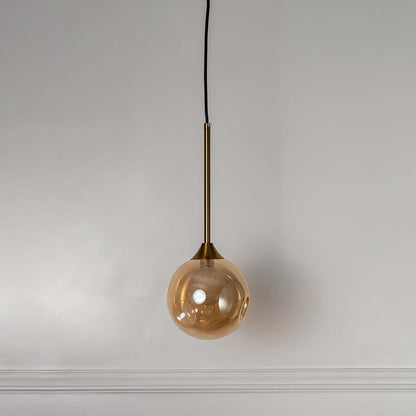 Modern amber glass globe pendant lamp with gold brass rod shown off on white background for home and dining decor.