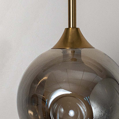 Closeup of smoked grey glass globe pendant lamp with gold brass rod highlighting elegant finish and premium design.