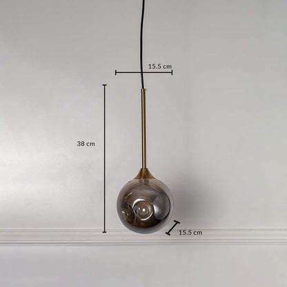 Smoked grey glass globe pendant light with gold brass rod illuminated on white background for stylish home lighting.