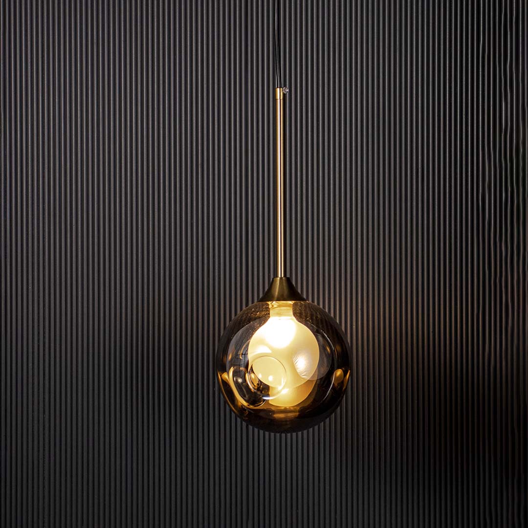 A modern glass globe pendant light switched on against a black textured background