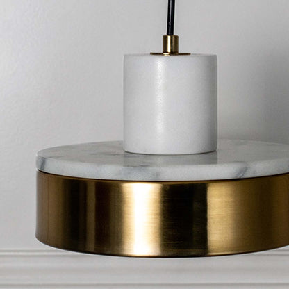 Closeup of pendant lamp with polished white marble and golden base shade highlighting premium luxury material design.