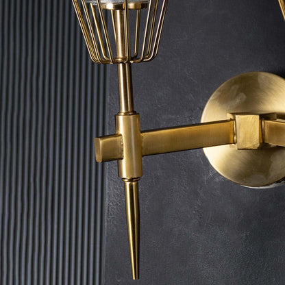 Macro shot of twin brass arms and sturdy wall mount plate of gold wall fixture highlighting durable construction and elegant finish.
