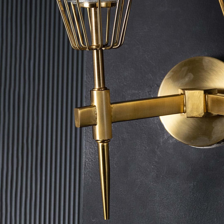 Macro shot of twin brass arms and sturdy wall mount plate of gold wall fixture highlighting durable construction and elegant finish.