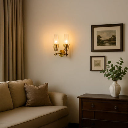 Double head gold torch wall sconce with tapered glass shades illuminated on cream living room wall above sofa creating warm ambiance.