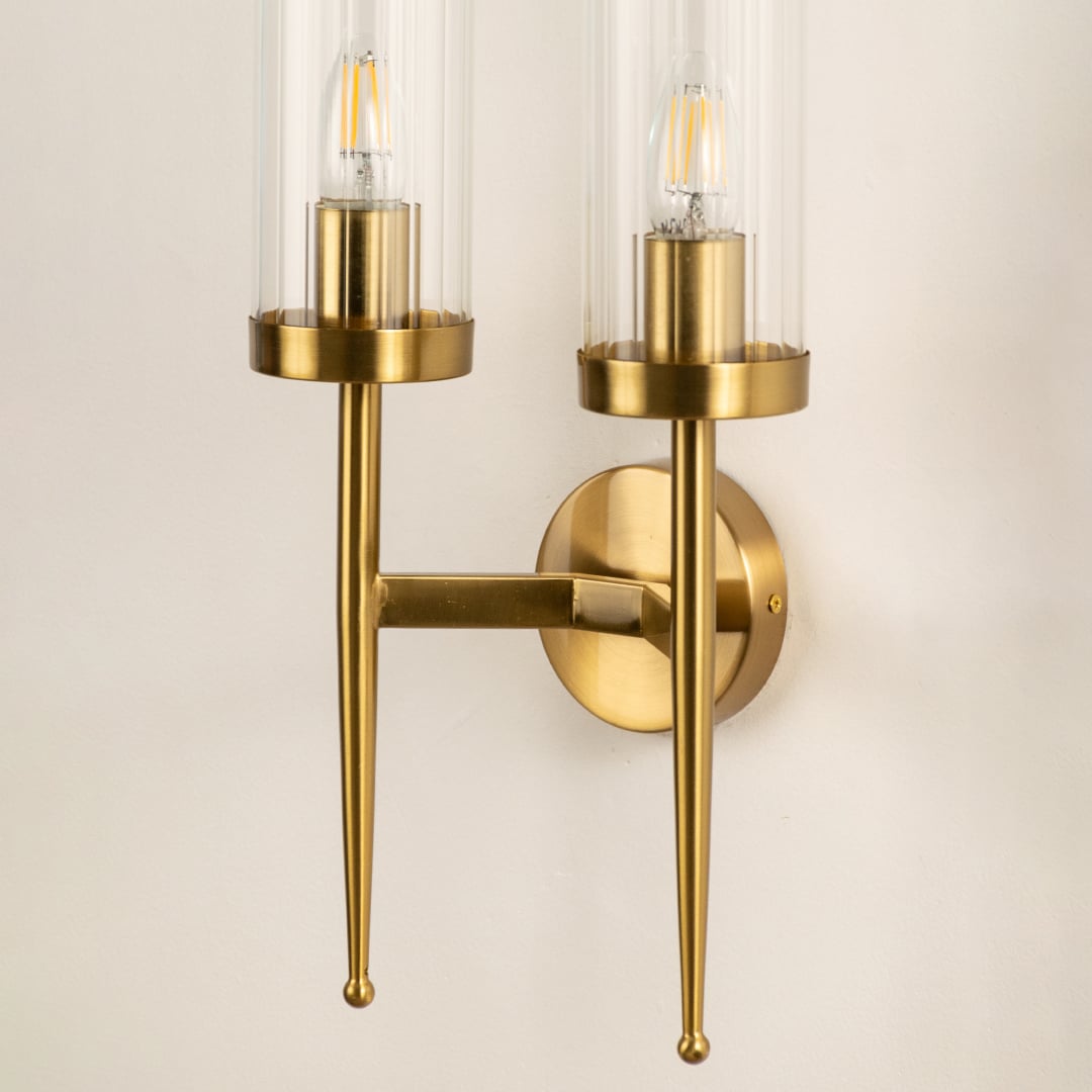 Closeup view of the double glass wall light displaying the transparent cylindrical shade and warm glowing filament bulb through the detailed glass.