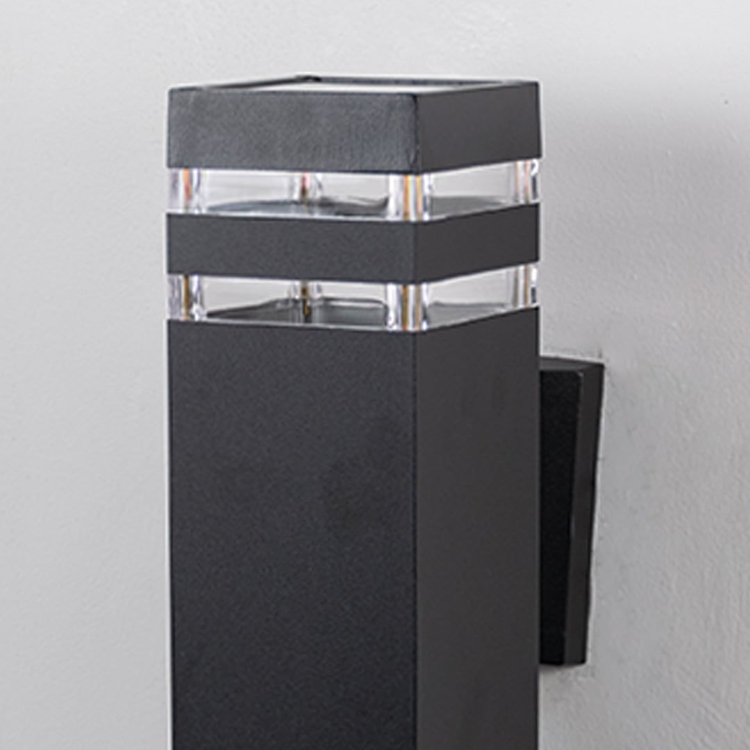 Closeup of rectangular black wall light featuring layered acrylic accents and smooth matte surface.