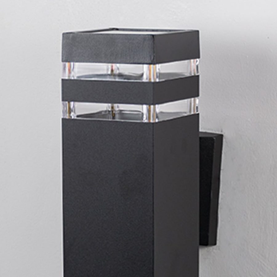 Closeup of rectangular black wall light featuring layered acrylic accents and smooth matte surface.