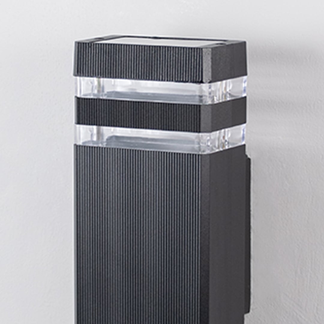 Closeup of black wall light showing fine ribbed texture and dual acrylic diffusers for even lighting.
