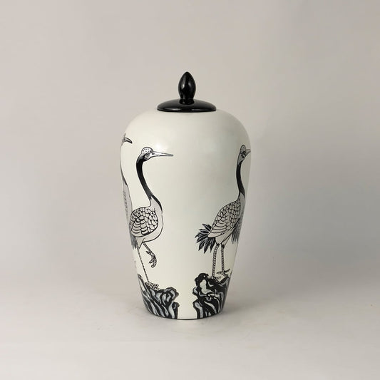 Side view of white ceramic jar with hand-painted crane pattern and black lid highlighting intricate artistic detailing.
