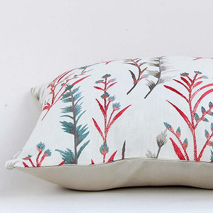 Closeup view of decorative cushion showcasing detailed red and teal botanical print on soft light off white fabric with smooth stitched edges and plush filling visible from the side.