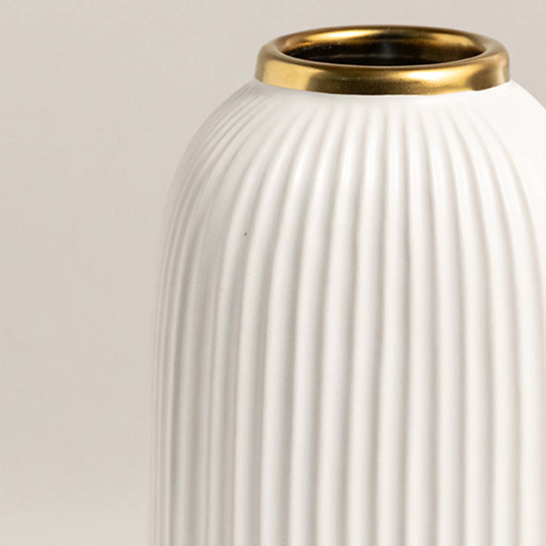 Closeup of white ceramic decorative vase with ribbed texture and gold rim showcasing premium craftsmanship details.