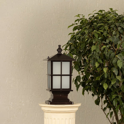 Black outdoor gate light styled beside green plants for elegant modern exterior decor ambiance.
