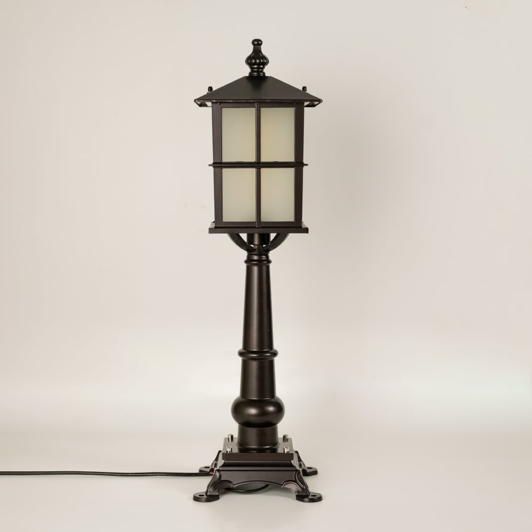 Vintage black outdoor gate light with frosted glass panels for elegant exterior decor use.