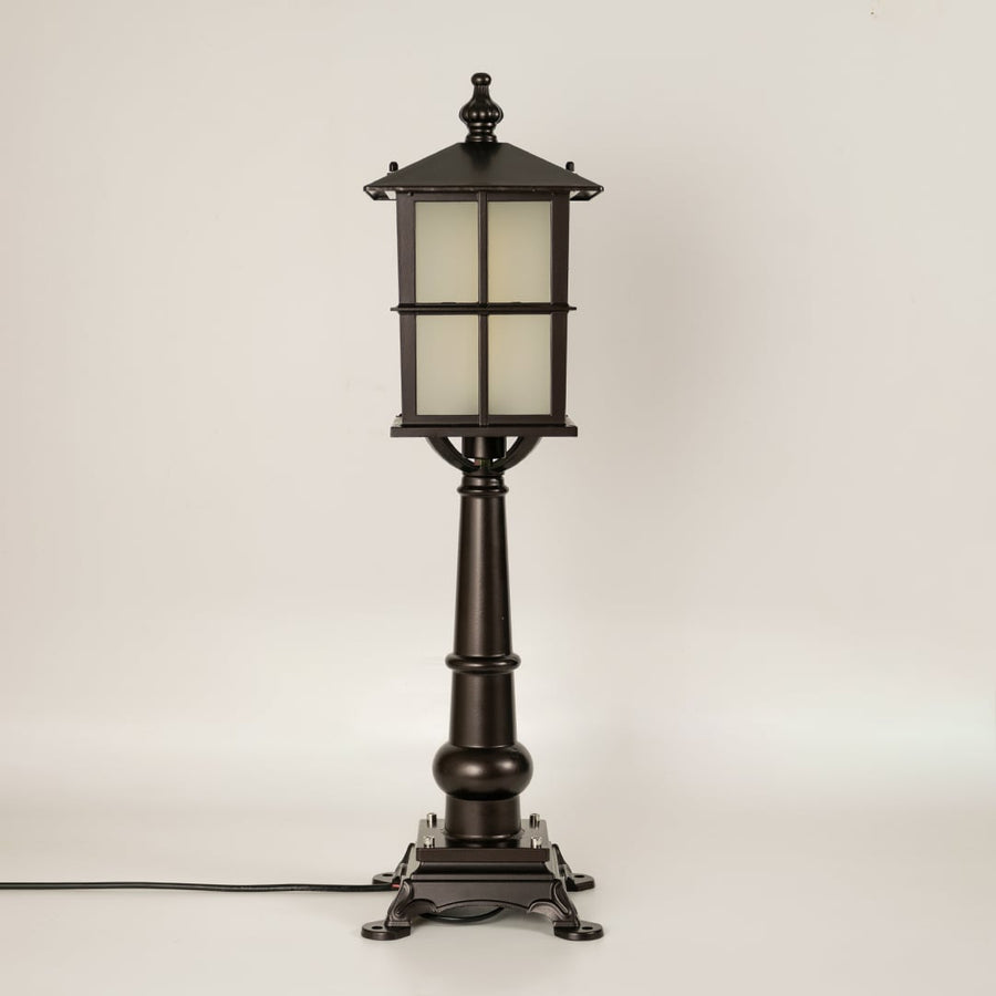 Vintage black outdoor gate light with frosted glass panels for elegant exterior decor use.