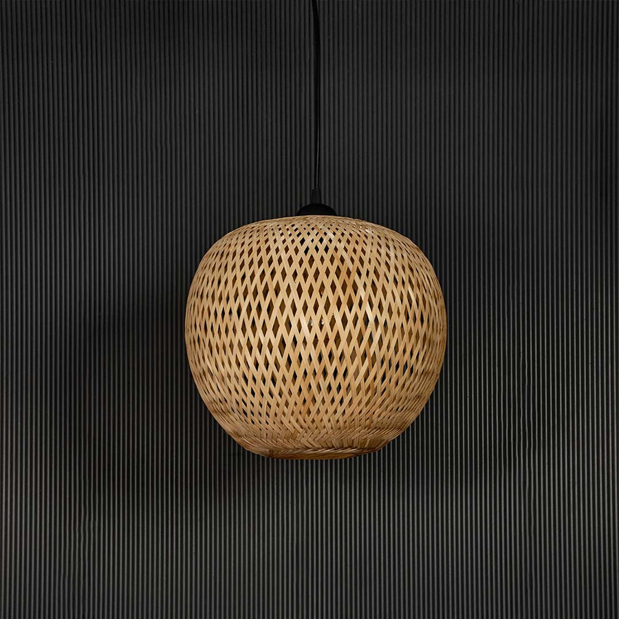 Round rattan pendant light with handwoven bamboo shade in natural finish turned off against plain black background.