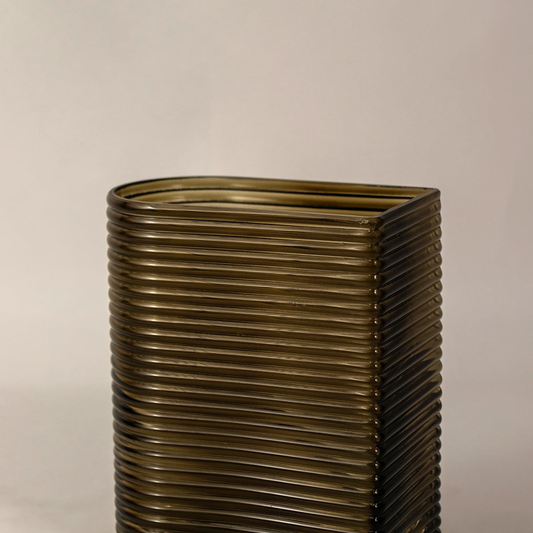 Closeup of ribbed glass vase in smoke brown finish showing curved rectangular shape and fine textured details for stylish placement.