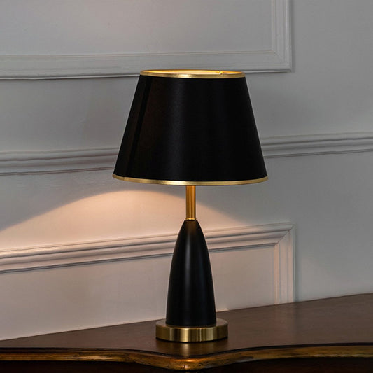 Black metal table lamp with black fabric shade displayed on a wooden console table creating sophisticated ambient lighting.