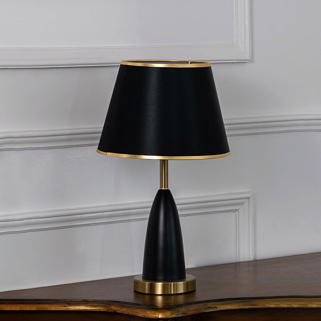 Black and gold table lamp with fabric shade turned off against white background elegant bedside decor table lamp.