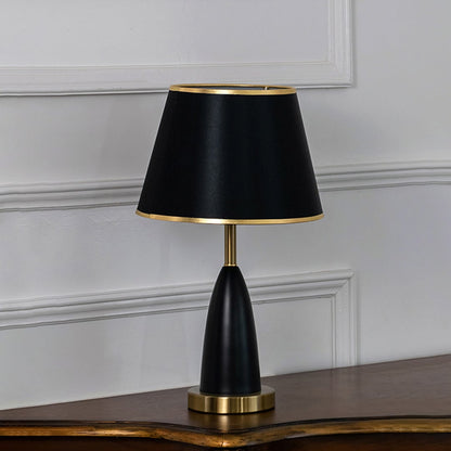 Black and gold table lamp with fabric shade turned off against white background elegant bedside decor table lamp.