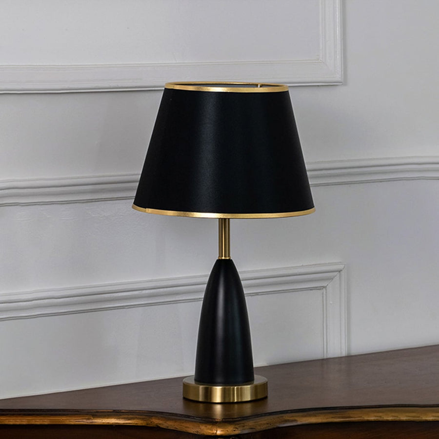 Black and gold table lamp with fabric shade turned off against white background elegant bedside decor table lamp.