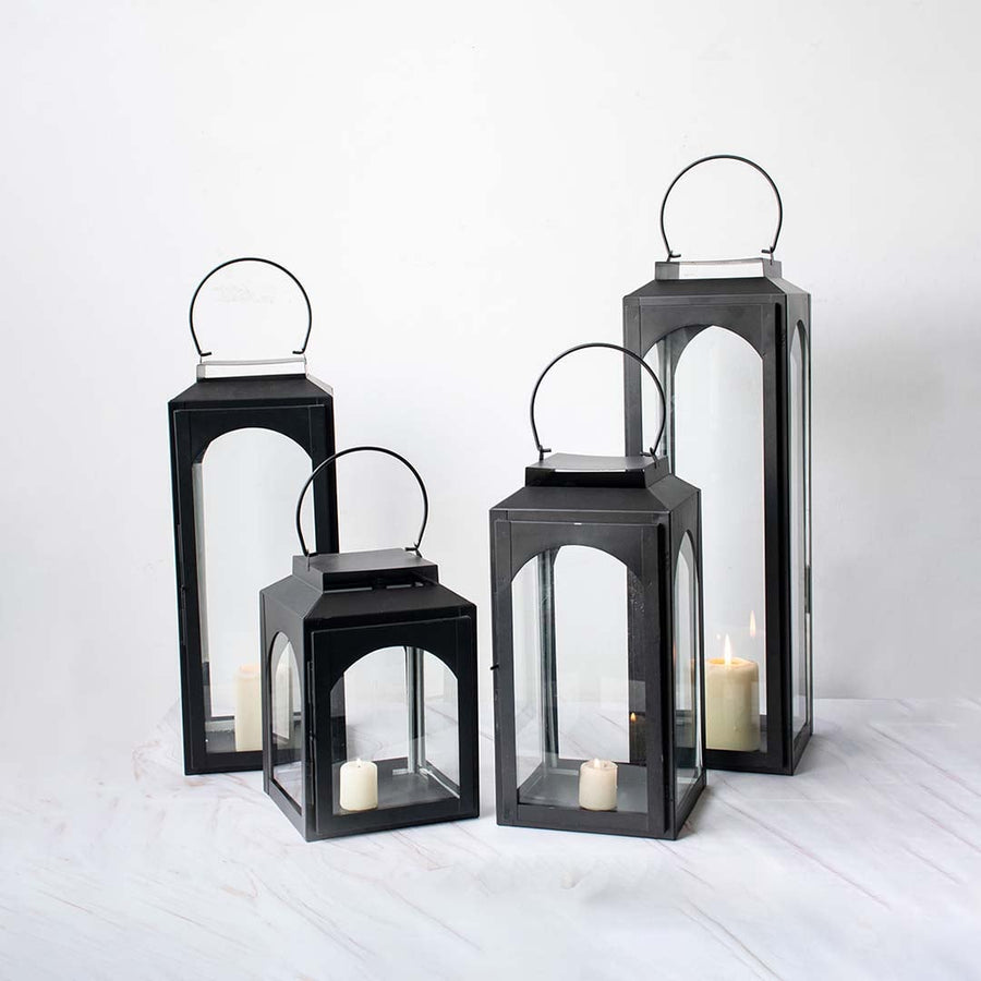 Set of black lanterns in different sizes with candles lit perfect for indoor and outdoor rustic decor.