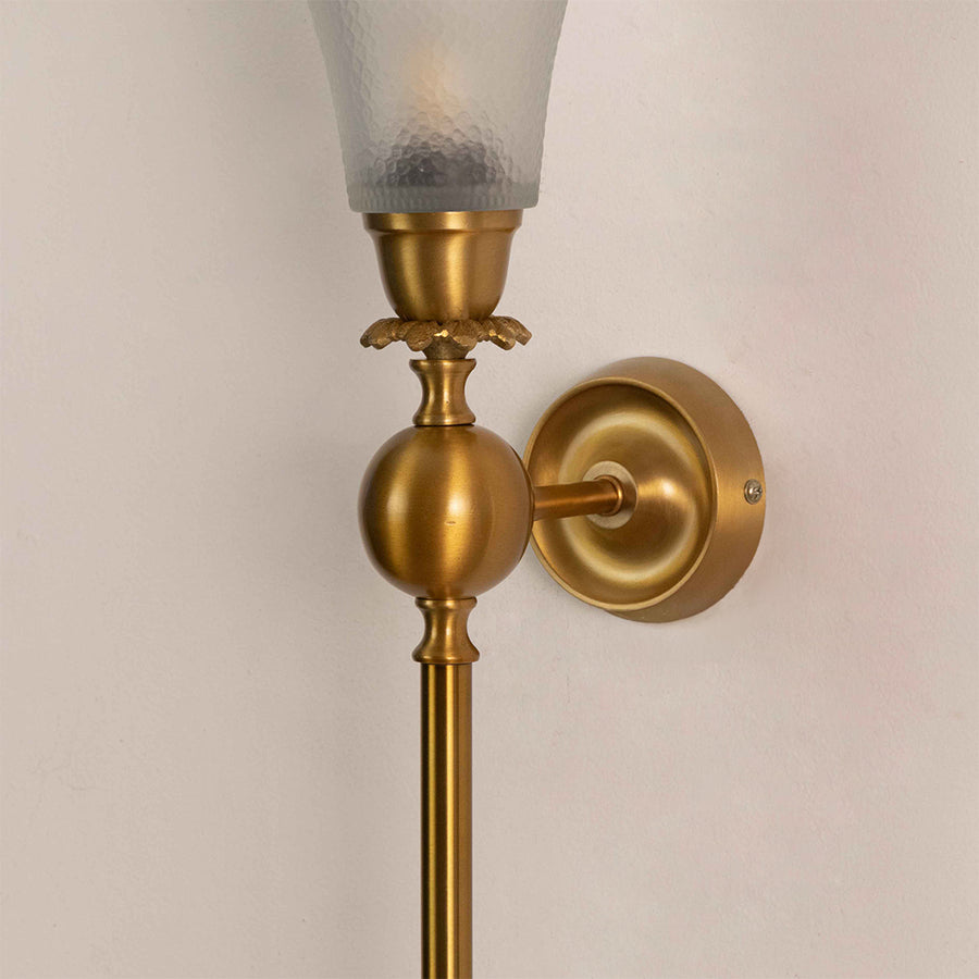 Closeup of gold metal wall light with frosted glass shade on white background ideal for bedroom hallway and living room decor.