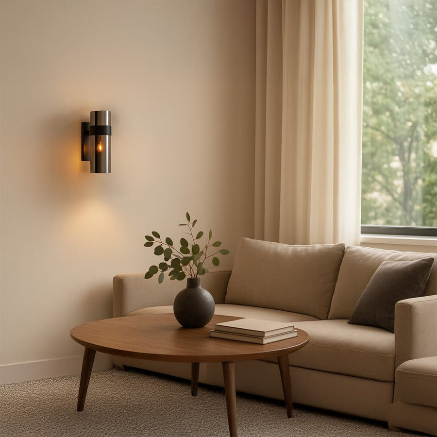A black metal wall light glowing softly beside a living room sofa on a beige wall adding warm accent lighting and stylish contemporary décor.