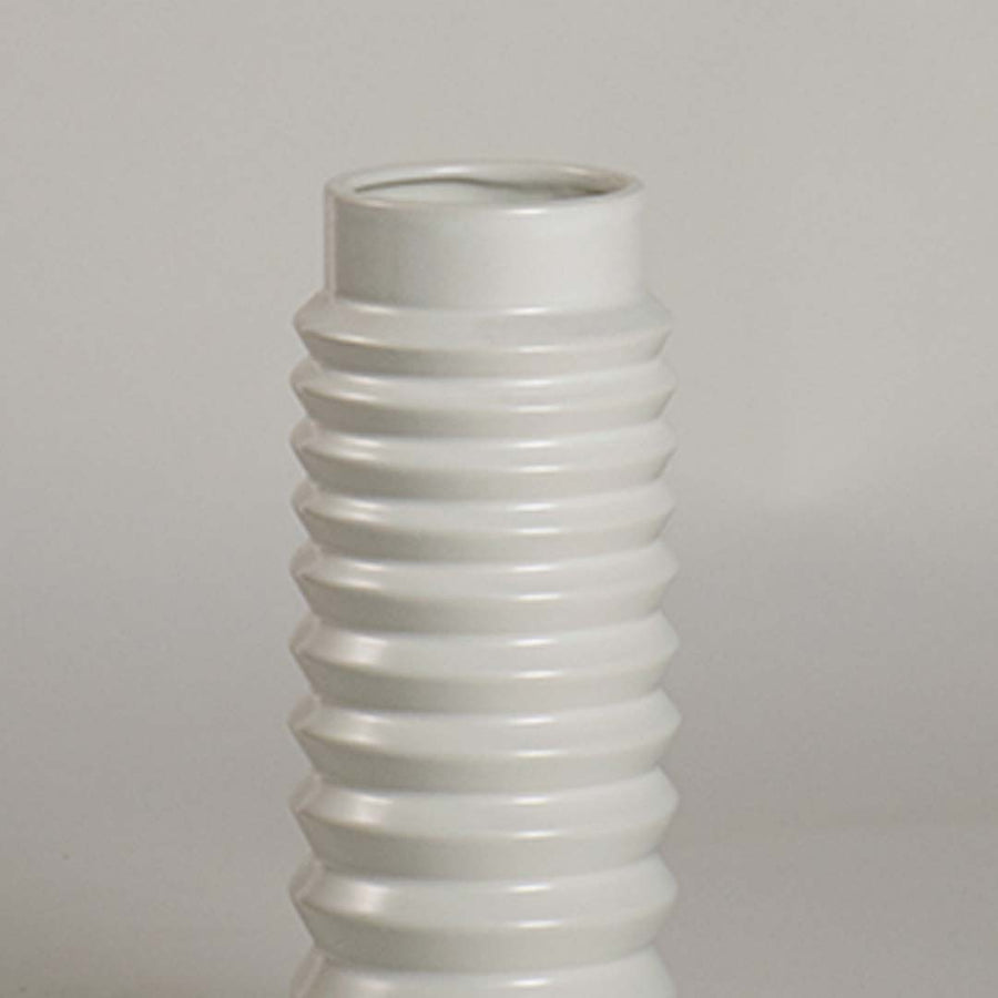 Closeup image of a matte white ceramic cylinder vase featuring a bold horizontally ribbed stacked ring pattern for art.