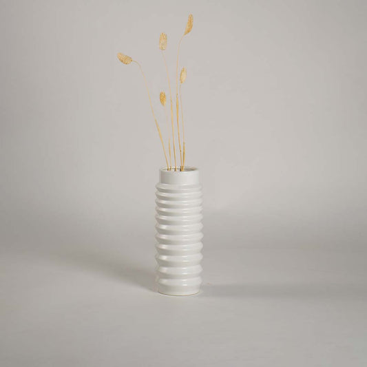White ceramic vase with ribbed design styled with dried stems adding elegance to minimal modern home decor.